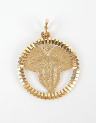 un gros plan d'un pendentif en or orné d'une feuille