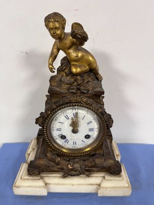 a small clock with a statue on top of it