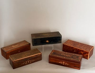 quatre boîtes en bois portant des inscriptions, posées sur une surface blanche