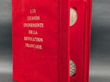 Le livre est ouvert, dévoilant une couverture rouge sur laquelle figure une pièce d'argent.