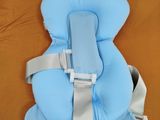 un siège bébé bleu posé sur un lit aux draps orange