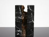 a statue of a woman standing in front of a black marble block