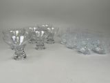six verres à pied en verre transparent sont alignés sur une surface blanche