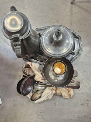 une théière en argent, accompagnée d'une tasse et de cuillères, posée sur une table