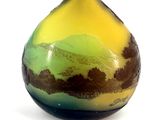 a yellow and green vase with a mountain scene on it