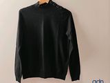 a black sweater hanging on a hanger against a wall