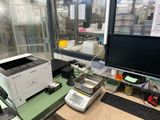 un ordinateur et une imprimante posés sur un bureau devant une grande fenêtre