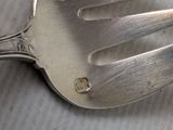 a silver fork with a hole in it sitting on a table