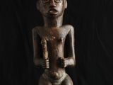 une statue en bois représentant un homme tenant un bébé dans ses bras, sur fond noir