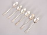 six silver spoons are lined up in a row on a white surface