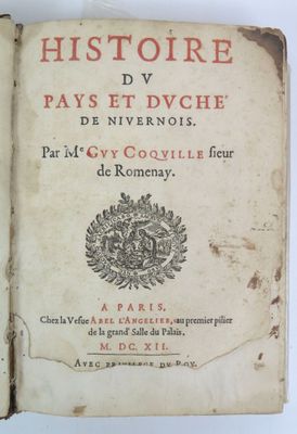 un vieux livre posé sur une table à côté d'une table blanche