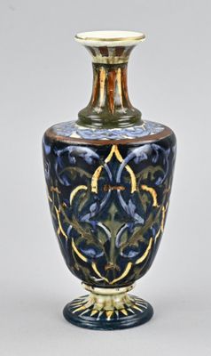 un vase bleu et or posé sur une surface blanche