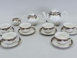 neuf tasses et soucoupes ainsi qu'une théière sur la table
