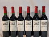 six bottles of red wine lined up in a row on a table