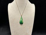 a necklace with a green tear shaped pendant on a mannequin