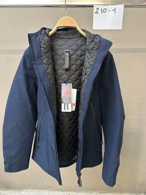 La veste est suspendue à un cintre devant un mur.