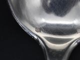 a silver spoon with a hole in it on a black surface