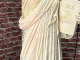 a statue of the statue of liberty in front of a brick wall