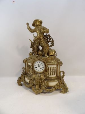 a gold clock with a statue on top of it