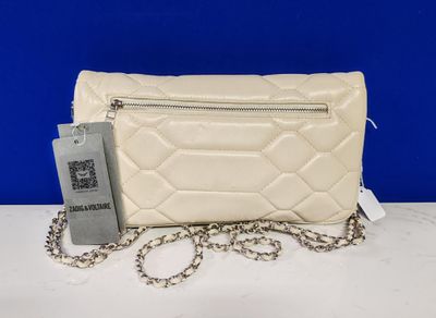 a white purse with a chain around it on a table