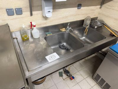 a sink in the middle of a kitchen with a lot of clutter