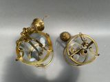 pair of brass - plated nautical compasses on a white surface