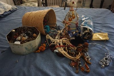 un panier de bijoux posé sur un lit, à côté d'un panier de perles