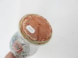 a hand holding a jar with a brown substance on it