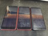 three iphones are sitting on a table with a glass on top