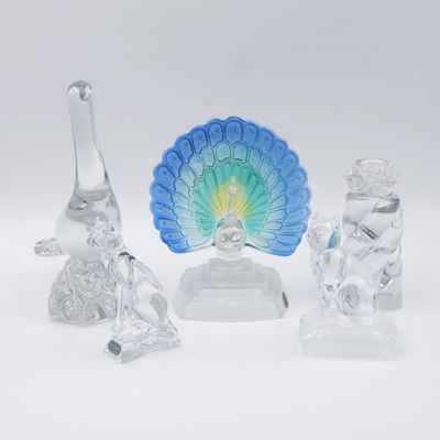 trois figurines en verre représentant des animaux et un paon, posées sur un fond blanc