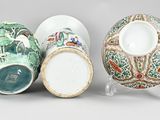 three chinese vases and a bowl on a stand on a gray surface