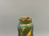 un vase vert et jaune posé sur une table