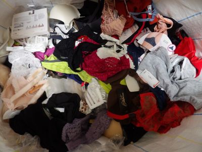 a large pile of clothing on a bed with a pair of scissors