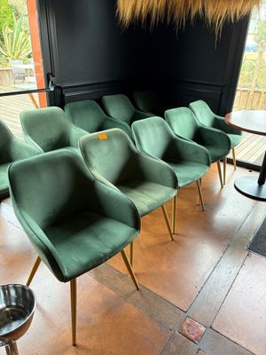 Plusieurs chaises vertes sont alignées en rang devant une fenêtre