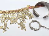 un collier en argent et en or et une paire de ciseaux posés sur une surface blanche