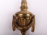 brass plated urn on a stand with a feather on top