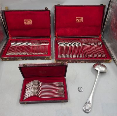 Plusieurs pièces d'argenterie se trouvent dans un coffret rouge posé sur une table