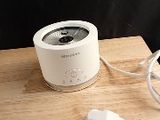 a small white speaker sitting on a table next to a charger