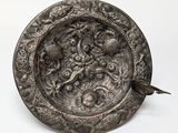 an old silver plate with a bird on it on a white surface
