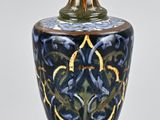 un vase bleu et or posé sur une surface blanche