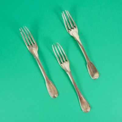 trois fourchettes et deux cuillères posées sur un support vert