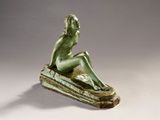 bronze statue of a woman sitting on a rock with her hand on her chin