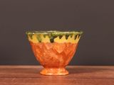 un petit bol orange posé sur une table en bois
