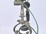 un téléphone à l'ancienne posé sur un socle, muni d'un cordon vert