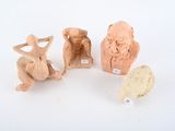 three clay figurines of different shapes and sizes on a white surface
