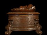 a bronze statue of a person laying on a box
