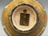 a gold and black vase sitting on a white surface