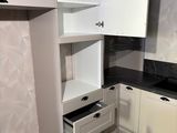 a small kitchen with white cabinets and black counter tops