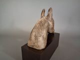 a sculpture of a dog sitting on top of a wooden block
