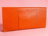 an orange leather wallet on a pink background